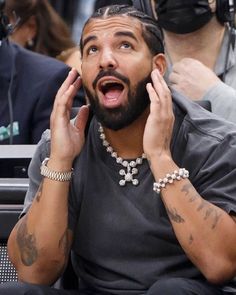 a man with his hands on his ears while looking at something in the air and making a funny face