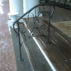 a bench sitting on top of a wooden floor next to a metal hand rail with snow all over it