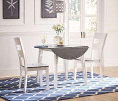 a dining room table with two chairs and a rug