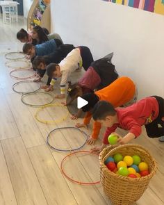 several children are playing with colored balls in a line on the floor while another child watches