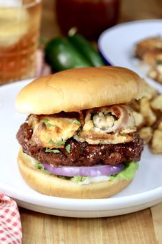 a sandwich with meat and onions on a plate next to some french fries, sitting on a wooden table