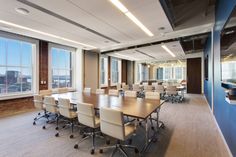 an empty conference room with white chairs and large wooden table in front of two windows