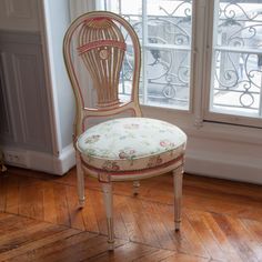 an old fashioned chair sitting on top of a hard wood floor next to a window