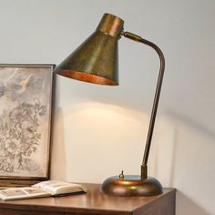 a desk lamp sitting on top of a wooden table next to a book and an open book