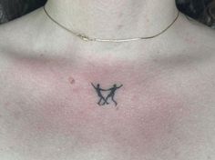 a woman's chest with a small tattoo of two cats on the back of her neck