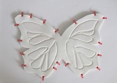 a white butterfly with red pins on it's wings