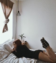 a woman laying on top of a bed next to a window