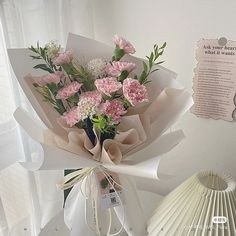 a bouquet of pink carnations wrapped in white paper