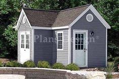 a small gray shed with a white door and windows