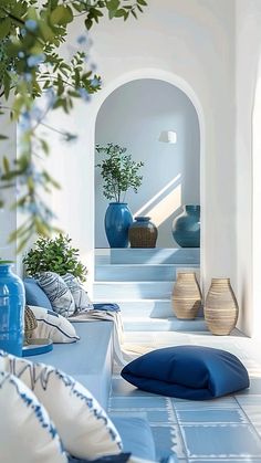 blue vases and pillows on the floor in a white room with stairs leading up to it