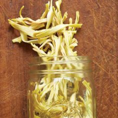 a jar filled with yellow flowers on top of a wooden table