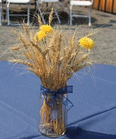 a vase filled with yellow flowers sitting on top of a blue tablecloth covered table