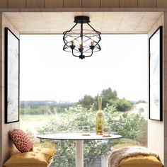 two chairs and a table in front of a window with a bottle of wine on it