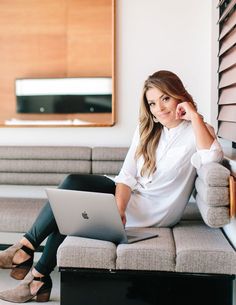 a woman sitting on a couch using a laptop computer