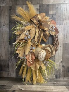 a wreath made out of burlocks and feathers on a wooden wall with wood planks