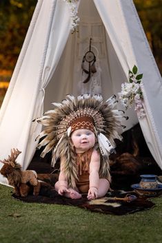 a baby sitting in front of a teepee