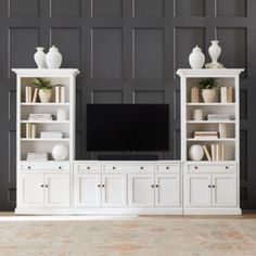 a white entertainment center with bookshelves and vases