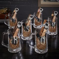 six clear mugs filled with different types of wine and cigars are sitting on a table