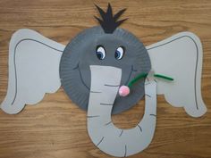 an elephant made out of paper on top of a wooden table with scissors in it