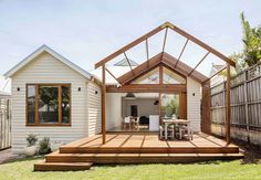 a house with a wooden deck in the back yard and an enclosed patio area on one side