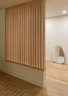 an empty room with wood slats on the wall and wooden flooring in front of a mirror