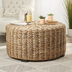 a wicker coffee table with potted plants and books on it in a living room