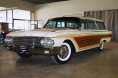 an old station wagon is parked in a large room with other antique cars behind it