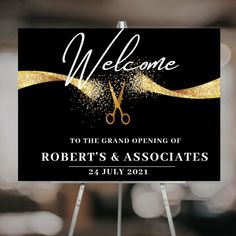 a welcome sign with scissors on it and gold glitters in the background, for a grand opening of robert's & associates 24 july 2012