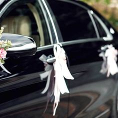 a black car decorated with flowers and ribbons for the bride's side view mirror