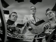 black and white photograph of three men in front of a mirror holding up cell phones