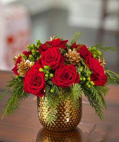 a gold vase filled with red roses and greenery