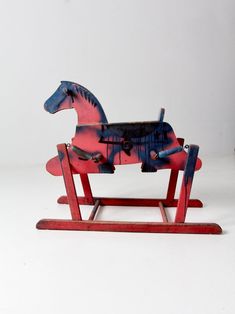 a wooden rocking horse painted red, white and blue with paint splattered on it