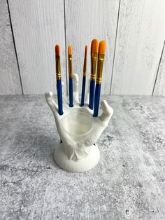 five brushes in a white holder on a table