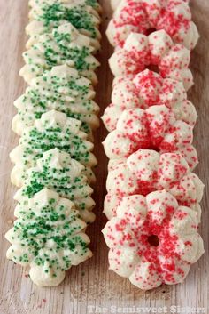 three christmas sprinkle donuts sitting on top of a wooden table next to each other