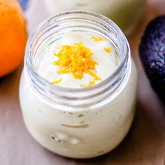 an avocado, orange and yogurt are sitting on the table next to each other