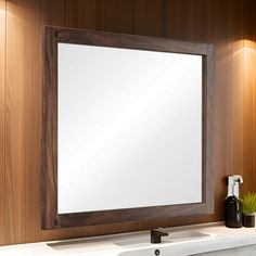 a bathroom mirror sitting on top of a wooden wall next to a white sink under a faucet