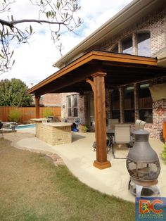 an outdoor covered patio with grill and seating area