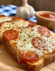 two slices of pizza sitting on top of a wooden cutting board next to a bowl of ketchup