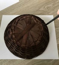 a person cutting into a chocolate cake with a knife on the table next to it