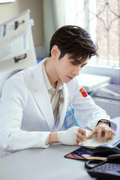 a man sitting at a desk writing on a piece of paper