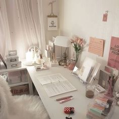 a white desk topped with lots of clutter and writing utensils next to a window