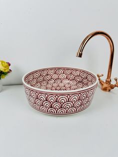 a sink with a faucet next to it and some flowers on the counter