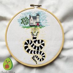 a cross stitch pattern with a house in the background and a black and white snake on it