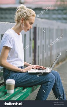 a woman sitting on a bench using a laptop computer