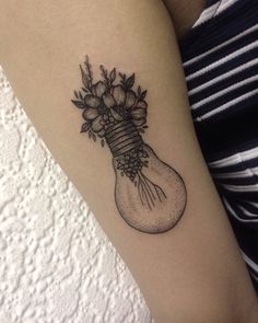 a tattoo on the arm of a woman with flowers in a lightbulb bulb