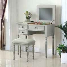 a white desk with a mirror, stool and potted plant in front of it