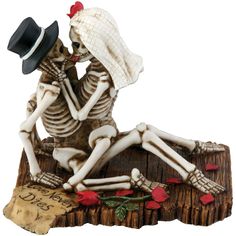 a skeleton figurine sitting on top of a piece of wood wearing a hat