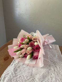 a bouquet of pink and white tulips on a lace tablecloth with a window in the background