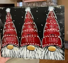 a painting of three red christmas hats with the words naught nice written on them