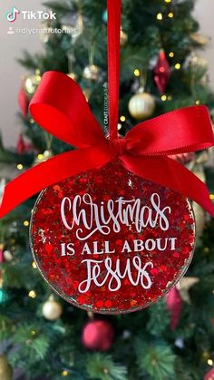 a christmas ornament hanging from the side of a christmas tree with red ribbon